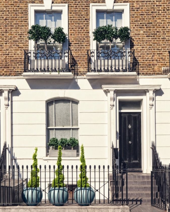 Georgian terraced house with white painted stucco ground floor, sash windows, a gloss black front door and black iron railings.